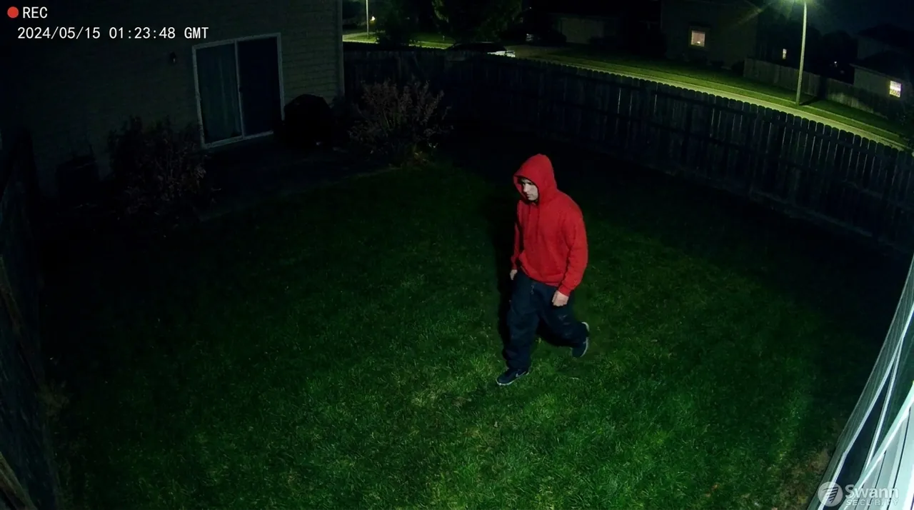 A figure walking across a backyard lawn