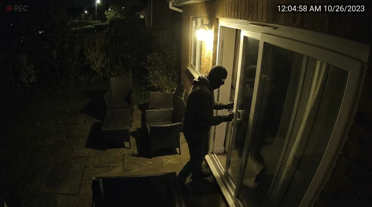 A masked figure opening a glass door